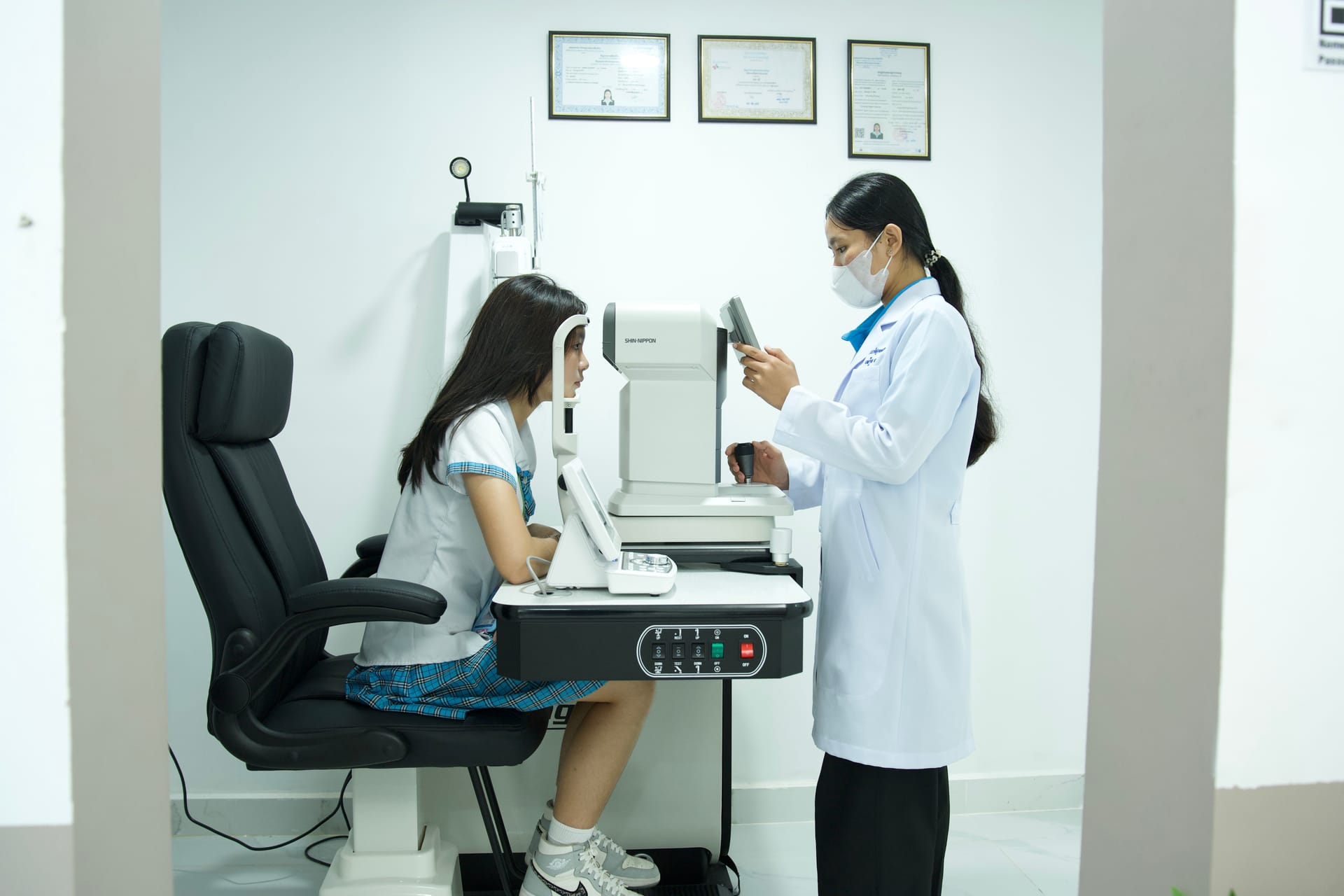 M-Optic optician conducting accurate computerized eye measurement using auto-refractor for pediatric vision test in Phnom Penh
